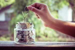 Hand putting coins in a jar