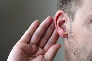 Man with hand to ear listening
