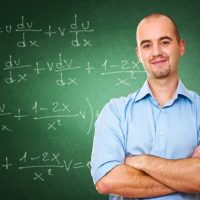 Male math teacher in front of a chalk board